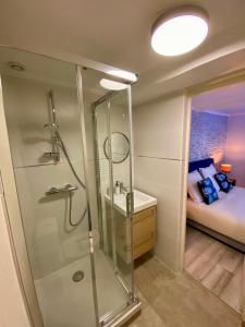 a bathroom with a shower and a sink and a bed at Chambres d'hôtes Le Maroni in Courseulles-sur-Mer
