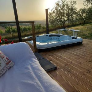 bañera de hidromasaje en una terraza con cama en Il Pozzo di Vivalpa en Serra deʼ Conti