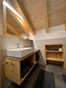 a bathroom with a white sink and wooden cabinets at Sartu Apartments in San Vigilio Di Marebbe