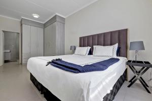 - un grand lit blanc avec une couverture bleue dans l'établissement Smart Apartment, à Midrand