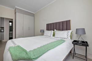 une chambre avec un grand lit blanc avec une couverture verte dans l'établissement Smart Apartment, à Midrand
