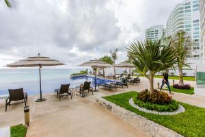 a patio with chairs and umbrellas next to the ocean at Condominio Girasol OceanView in Cancún