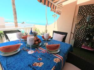 een tafel met een blauwe tafeldoek met fruit erop bij Charming Sunset View Apt Heater Pool Costa Adeje in Adeje