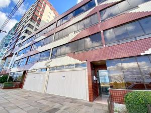 a red brick building with a white garage at Apto Beira Mar 3D in Capão da Canoa