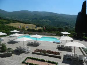 an outdoor swimming pool with umbrellas and chairs at Le Gret in Subbiano