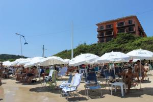a group of people sitting in chairs under umbrellas on a beach at Destino Floripa Jurerê Beach Village in Florianópolis