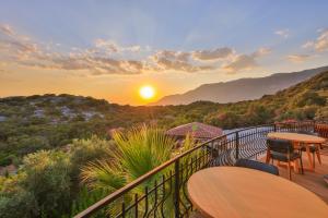 a balcony with tables and chairs and the sunset at Hill House Adult Only in Kaş