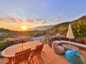 a deck with a table and chairs and a sunset at Hill House Adult Only in Kaş