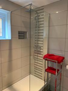 a glass shower with a red towel on a stool at The Croft in Sandhurst +20 photos