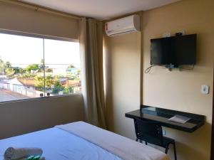 a hotel room with a bed and a desk and a window at Pousada e Restaurante MKE in João Pessoa