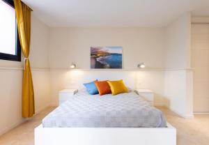 a bedroom with a white bed with orange and blue pillows at Sunny Castillo Apartment in Costa de Antigua +33 photos