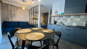 een keuken met een tafel en stoelen en een keuken met een bank bij Apartament MAGMA z basenem Morska Klifowa Rewal in Rewal
