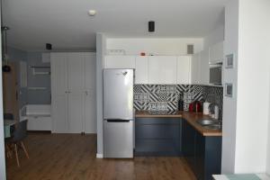  La cuisine est équipée de placards blancs et d'un réfrigérateur. dans l'établissement Apartament Rodzinny Jantar Park, à Jantar