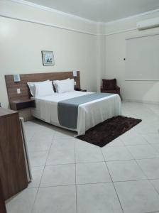a hotel room with a bed, chair, and nightstand at Hotel Mais in Macapá