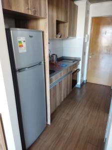 a kitchen with a white refrigerator and wooden cabinets at Depto.Barcelona Rucakawi in Temuco