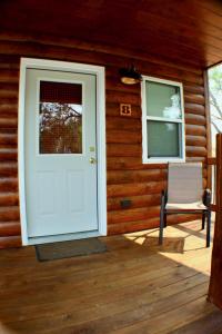 una puerta blanca en una cabaña de madera con una silla en Shell Campground en Shell