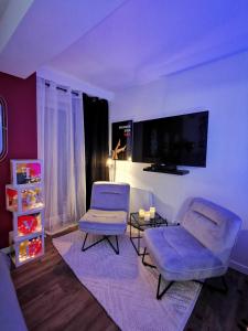 ein Wohnzimmer mit 2 Stühlen und einem Flachbild-TV in der Unterkunft LoveSparadise -Suite Le Secret in Saints