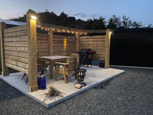 a patio with a table and a grill with lights at Glens glamping in Cushendall