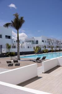 a resort with a pool and a palm tree and buildings at Island Home Fuerteventura in Corralejo
