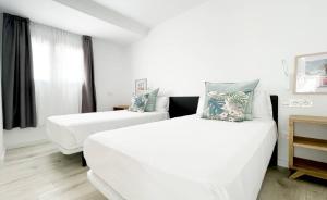 a white room with two beds and a window at Island Home Fuerteventura in Corralejo