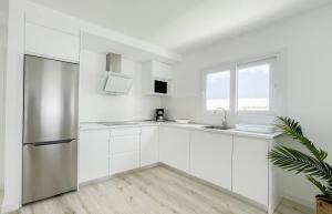 a kitchen with white cabinets and a stainless steel refrigerator at Island Home Fuerteventura in Corralejo