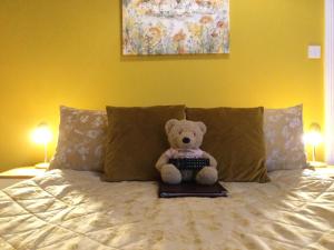 a teddy bear sitting on a bed with a keyboard at Arun Sands Rooms in Littlehampton