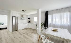 a white kitchen and dining room with a table and chairs at Island Home Fuerteventura in Corralejo