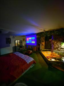 1 dormitorio con 1 cama y TV grande en Cosmos Chill - Suite con jacuzzi y acuario, en Ambato