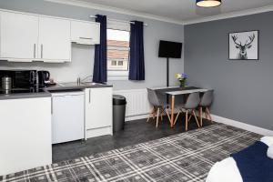 a kitchen with white cabinets and a table and chairs at St Andrews Guest House in Irvine