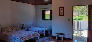 Un dormitorio con dos camas y una ventana en Pousada Pedacinho do Céu -Chalé Familia, en Cunha