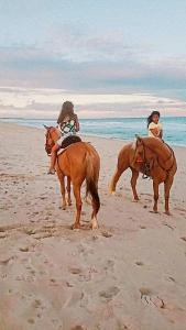 two women are riding horses on the beach at Rancho da Doris in Barra de São Miguel