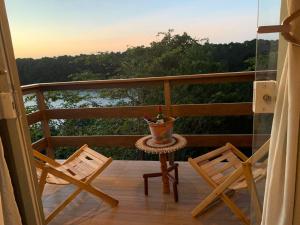 einen Balkon mit 2 Stühlen und einer Kanne auf einem Tisch in der Unterkunft Chalé do Rio in Barreirinhas