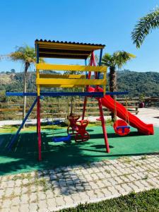 um parque infantil com um escorrega colorido e um baloiço em SÍTIO MARAVILHOSO EM MAIRIPORÃ opção de 1 quarto para 8 pessoas ou 4 quartos acima de 9 pessoas em Mairiporã