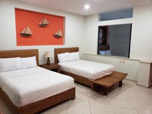 a bedroom with two beds and a painting of boats at Carasol Villas y Suites Privadas in Ciudad Madero