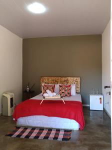 - une chambre avec un grand lit et une couverture rouge dans l'établissement Sítio Aroeira Chalés, à Sao Jorge