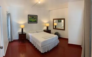 a bedroom with a white bed and a mirror at Palmira Hostel in Tegucigalpa