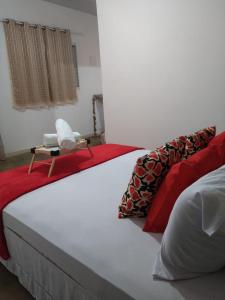Una cama grande con almohadas rojas y blancas. en Sítio Aroeira Chalés, en São Jorge