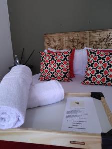 a towel on a bed with pillows and a menu at Sítio Aroeira Chalés in Sao Jorge