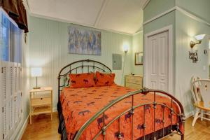 a bedroom with a bed with an orange comforter at Linville River Cottage - Steps Away From The Banks in Newland