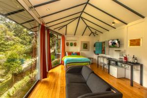 sala de estar con sofá y cama en una habitación en Dantica Cloud Forest Lodge, en San Gerardo de Dota