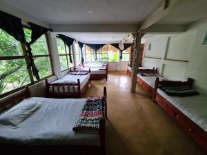 a bedroom with three beds and a room with windows at Casa AHAU in San Marcos La Laguna