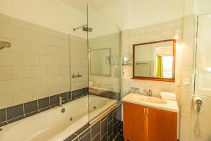 a bathroom with a tub and a sink and a mirror at Dantica Cloud Forest Lodge in San Gerardo de Dota