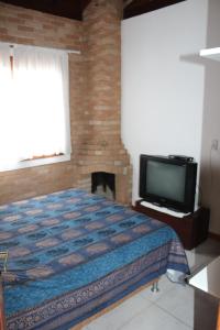 - une chambre avec un lit, une télévision et une cheminée dans l'établissement RECANTO HARMONIA, à Conceição da Ibitipoca