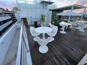 a balcony with white tables and chairs and an umbrella at Israel Flat Tambaú in João Pessoa