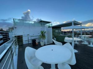 a balcony with white tables and umbrellas on a building at Israel Flat Tambaú in João Pessoa