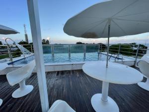a table and chairs with an umbrella on a deck at Israel Flat Tambaú in João Pessoa