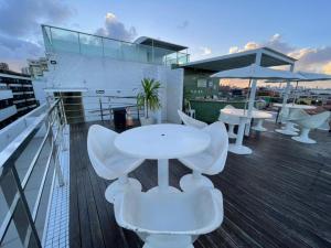 a balcony with white tables and chairs on a building at Israel Flat Tambaú in João Pessoa