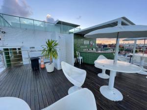 a balcony with a table and chairs and an umbrella at Israel Flat Tambaú in João Pessoa