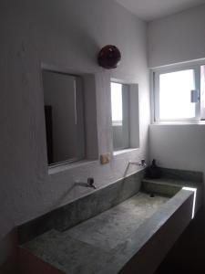 baño con lavabo grande y espejo grande en Hostal Jardin, en Mahahual