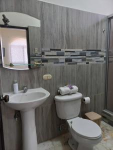 a bathroom with a sink and a toilet and a mirror at Del Sol Suites - Apartamento #1 in Guayaquil